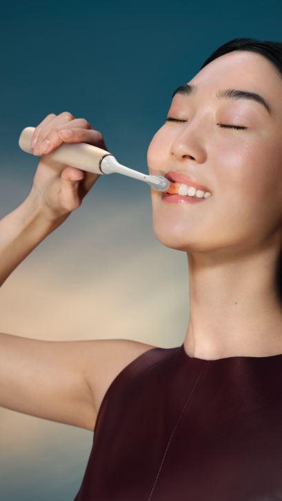 A woman brushing with a Philips Sonicare 9900 Prestige