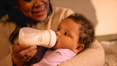 Mother feeding baby with Philips Avent bottle at home