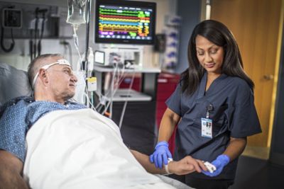 Clinician checking patient monitoring device in hospital room