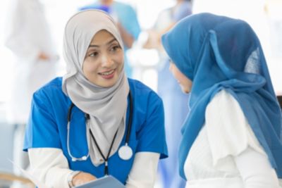 Female Muslim nurse talking compassionately to a patient