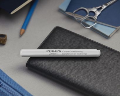 A Philips Zoom! whitening pen resting on a desk with objects