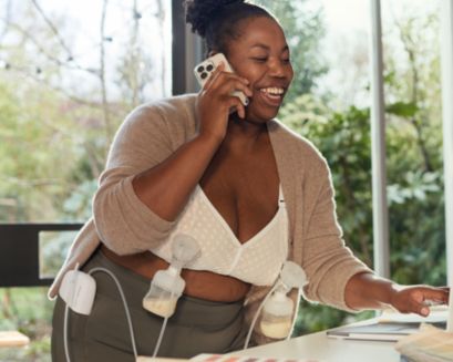 Mom talking to the phone while wearing breast pumps