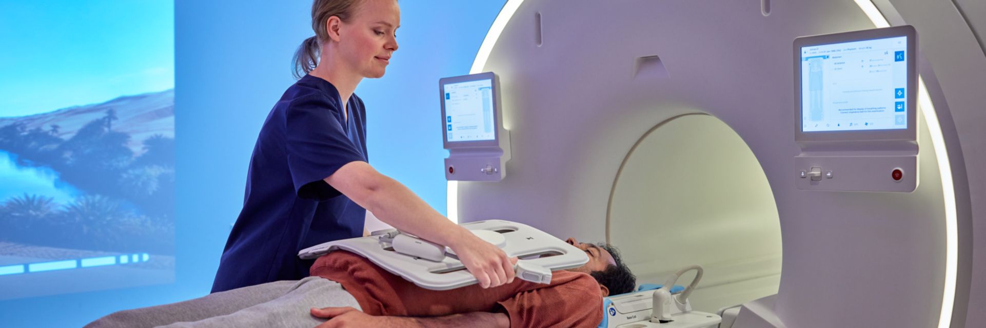 Technologist with patient entering MR scanner, positioning coil