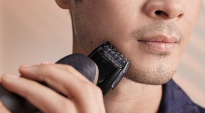 Hombre recortando la barba com una afeitadora el&eacute;ctrica, preparando el afeitado en mojado.