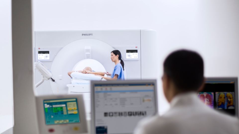 Radiologist looking at spectral data on workstation with IQon Spectral CT in background