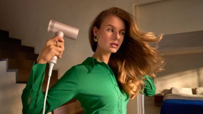 Frau, die sich zu Hause mit einem Föhn die Haare trockne
