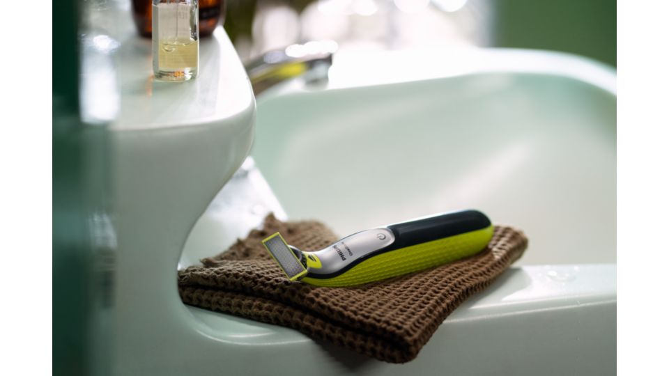 A Philips OneBlade 360 sits by a bathroom sink.