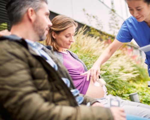 Vader en moeder met een riemloze pod en pleister buiten het ziekenhuis