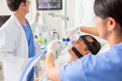 Noninvasive ventilation (NIV) mask being used on patient by clinicians in hospital.