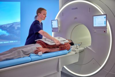 Técnico en radiología posicionando al paciente en la sala de resonancia magnética de Philips con experiencia ambiental
