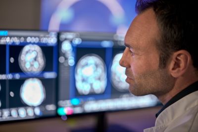 A clinician reviewing brain images on desktop monitor