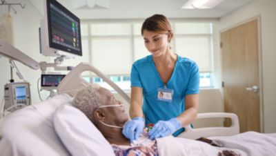Clinician caring for hospitalized patient with Philips bedside patient monitoring display